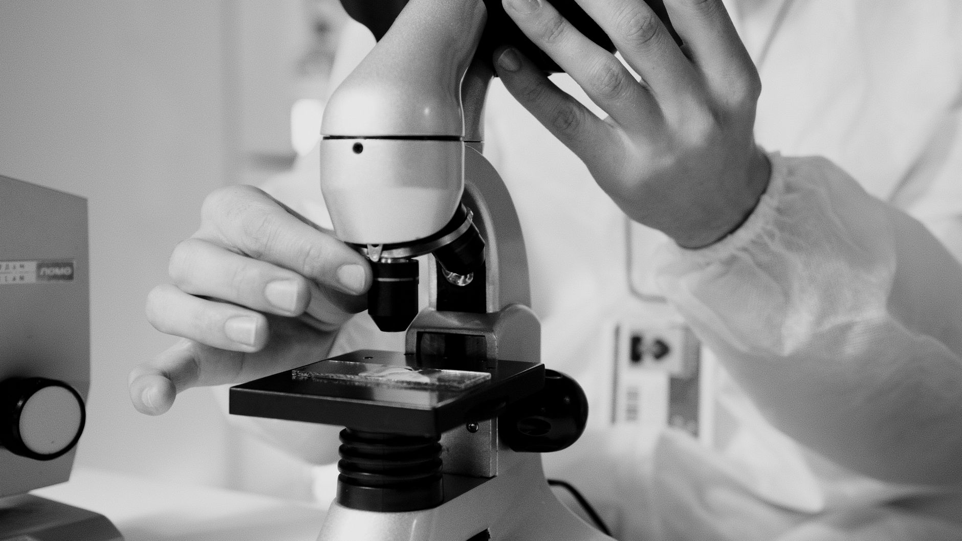 Mains gantées tenant un flacon en verre scellé à côté d'un équipement d'analyse dans un laboratoire de recherche